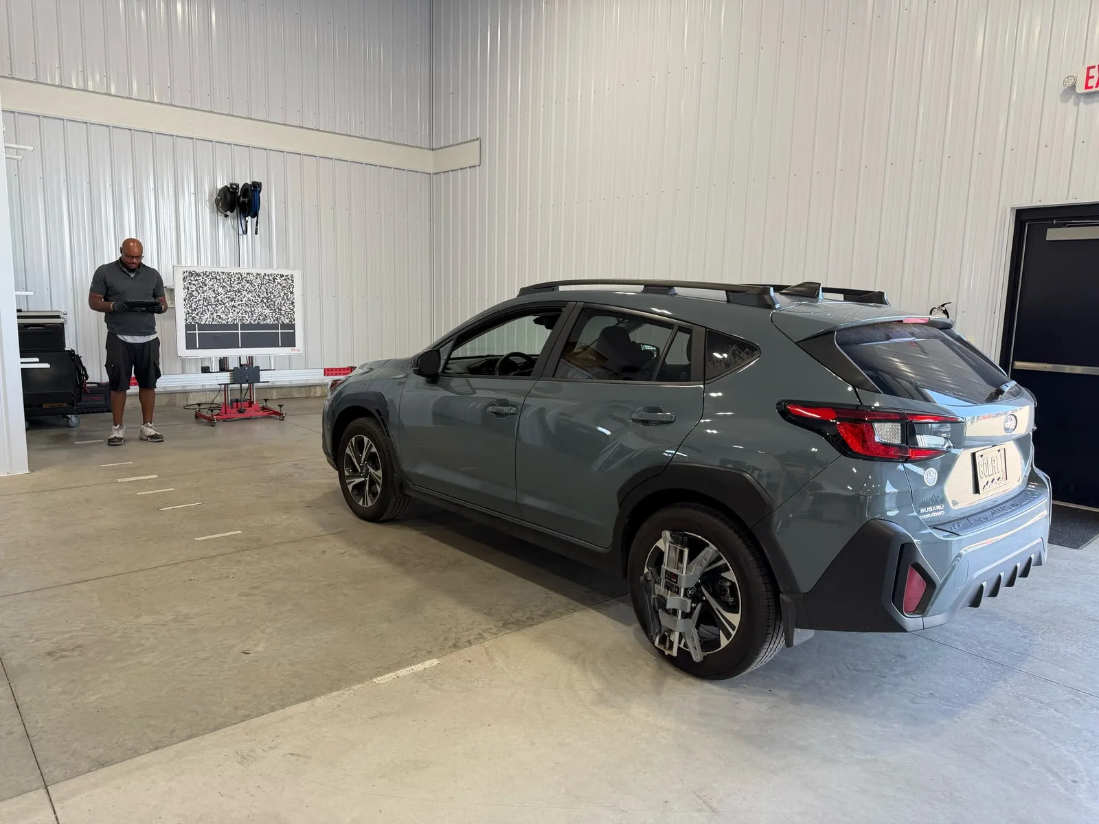A Subaru Crosstrek in the Glass Enterprise bay in front of an ADAS calibration target board
