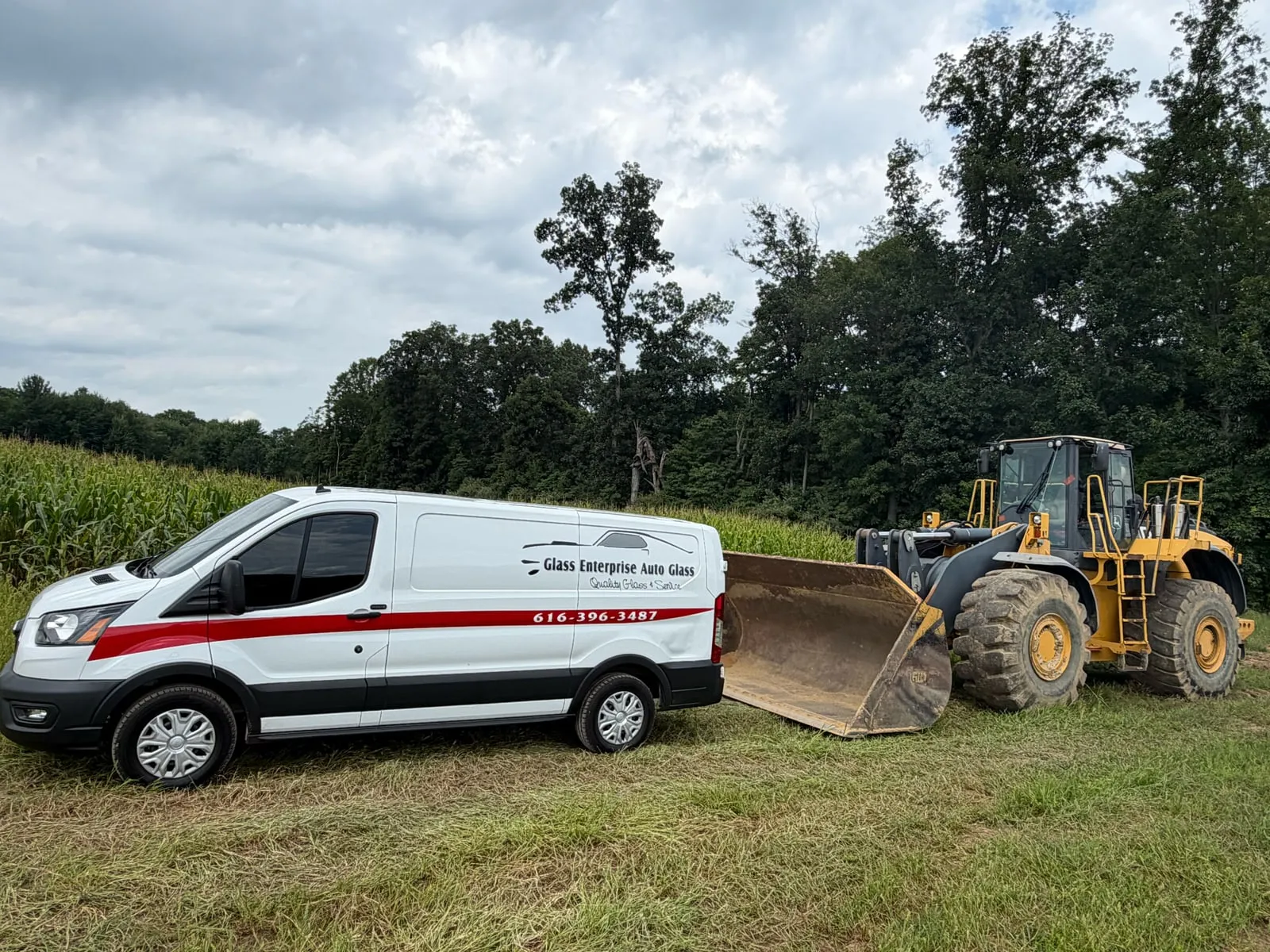 A Glass Enterprise Auto Glass service van parked beside a wheel loader on a job site
