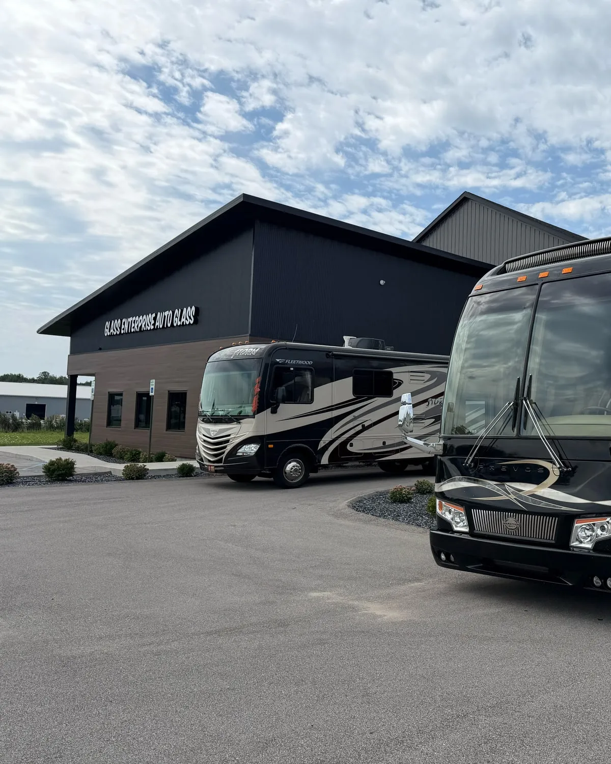 A motorhome and a motorcoach parked outside the Glass Enterprise Auto Glass shop on 58th Street in Holland, Michigan