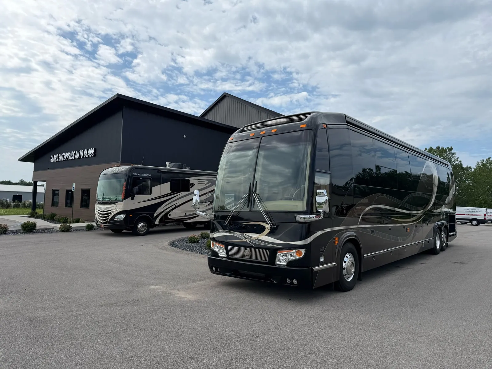 A motorcoach and a motorhome parked outside the Glass Enterprise Auto Glass shop in Holland, Michigan